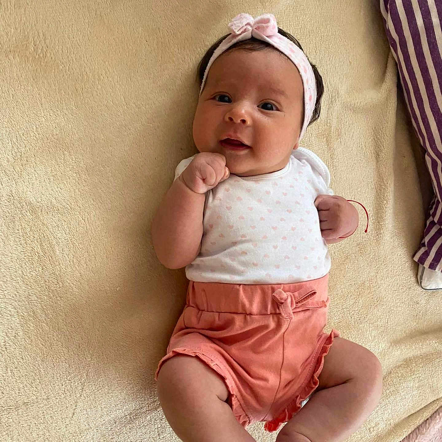 Laura participe au concours pour gagner de l'argent avec cette photo : arms, baby, blanket, bow, child, clothing, cute, face, happy, headband, indoors, infant, legs, lying_down, person, pink, skin, smile, soft_texture, white