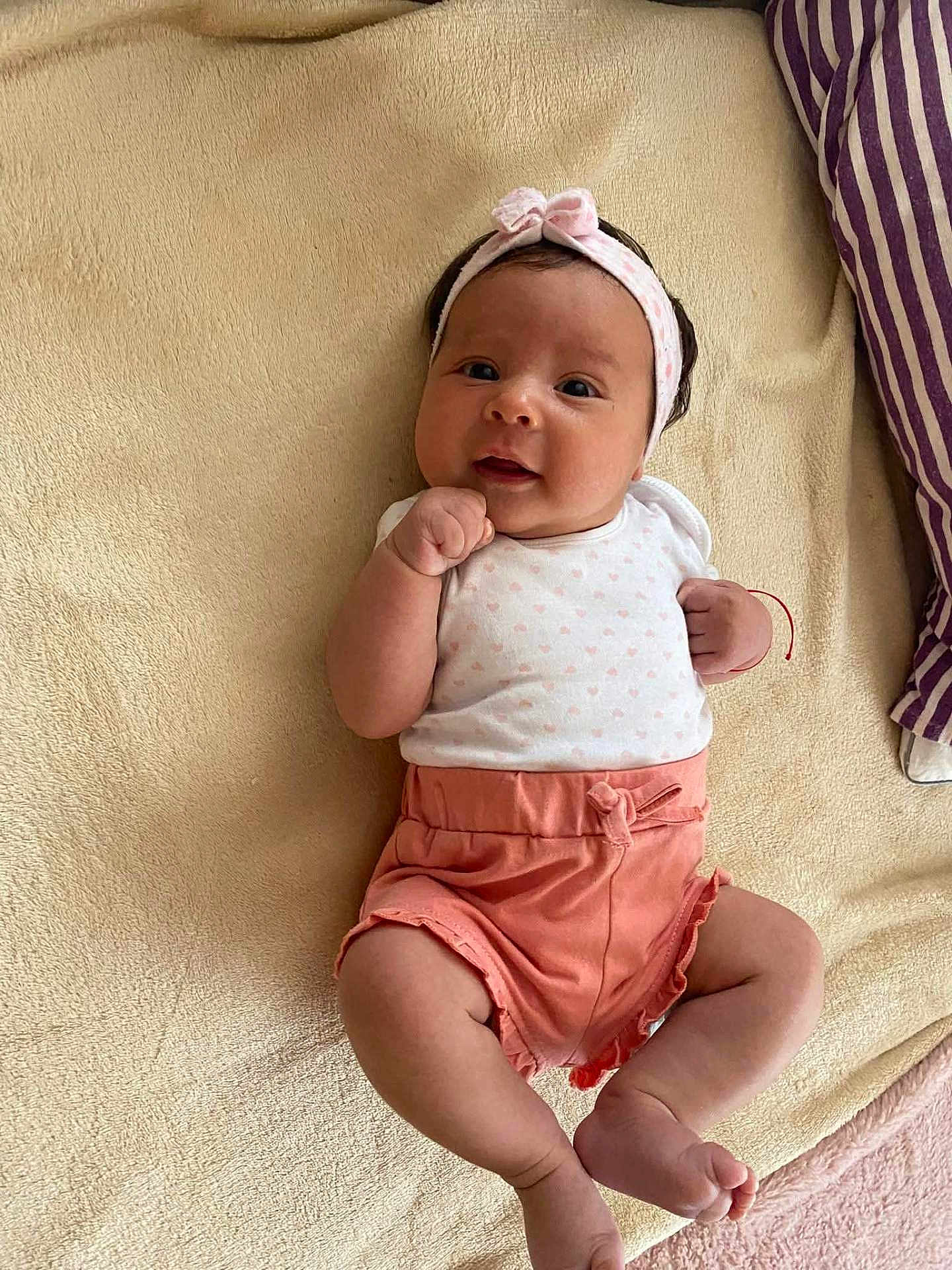Laura participe au concours pour gagner de l'argent avec cette photo : baby, infant, child, headband, bow, blanket, soft_texture, clothing, pink, white, cute, smile, lying_down, indoors, skin, person, legs, arms, face, happy
