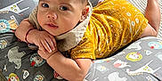 Jason is registered to the contest to win money with this photo: baby, infant, pillow, yellow_clothing, animal_pattern, carpet, cute, child, indoors, portrait, resting, looking_at_camera, colorful, soft_lighting, hand, face, head, floor, laying_down, comfortable
