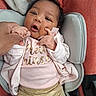 Kyra'Yana joined the competition — help win amazing prizes! baby, infant, child, portrait, sitting, car_seat, pink_clothing, sparkly_pants, blanket, cushion, adult_hand, finger, open_mouth, wide_eyes, curly_hair, indoor, close_up, cozy, text_on_clothing, happy