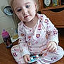 Madalynn joined the competition — help win amazing prizes! child, toddler, pajamas, floral_pattern, sitting, barefoot, blue_eyes, holding, package, table, wooden, cup, drink, bookshelf, books, indoors, face, person, cute, smiling
