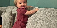 Madalynn joined the competition — help win amazing prizes! toddler, child, standing, couch, indoor, smiling, hair_pigtails, pink_socks, dress, gray_couch, wall, person, happy, furniture, home, playful, infant, young_child, cute, portrait