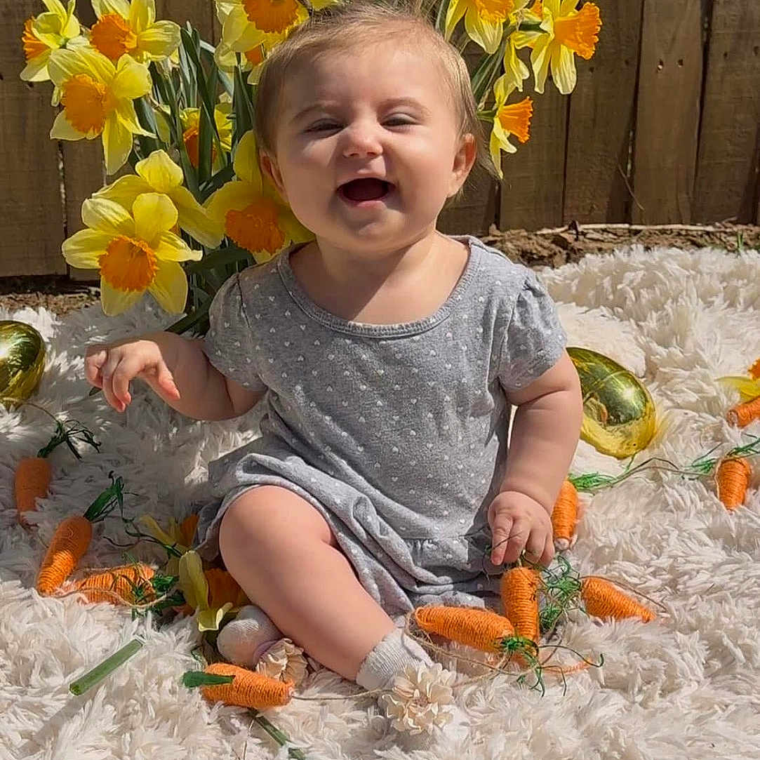 Madalynn is registered to the contest to win money with this photo: baby, carrot, child, cute, daffodil, decoration, fence, flower, garden, grass, happy, nature, outdoor, person, playful, rug, sitting, smiling, spring, sunlight