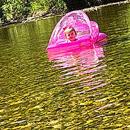 Madalynn is registered to the contest to win money with this photo: child, toddler, inflatable_boat, pink, water, river, rocks, nature, trees, outdoor, sunlight, reflection, canopy, floating, baby, playful, summer, daylight, person, recreation