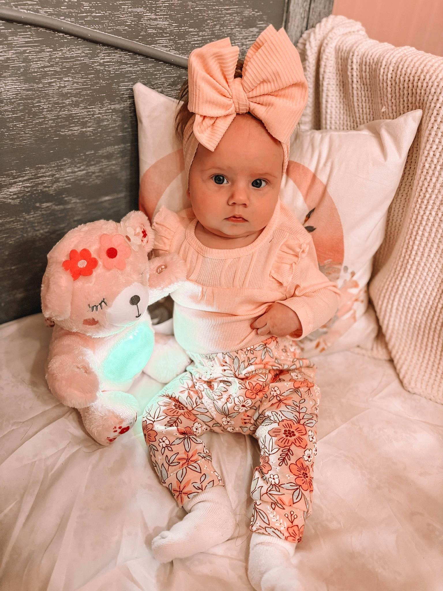 Oaklee is registered to the contest to win money with this photo: arm, baby, baby_toddler_clothing, comfort, doll, dress, eye, eyelash, happy, headwear, linens, mammal, orange, peach, person, pink, sitting, skin, sleeve, textile