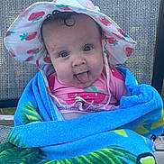 Greta joined the competition — help win amazing prizes! baby, child, towel, hat, strawberry, blue, pink, tongue, smiling, outdoor, chair, woven, cute, portrait, person, face, summer, playful, happy, wrapped