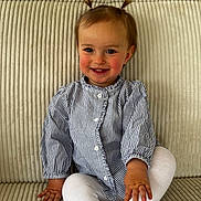 Mila participe au concours pour gagner de l'argent avec cette photo : toddler, child, smiling, pigtails, striped_shirt, white_leggings, sitting, couch, beige, soft_furniture, happy, portrait, indoors, cute, young_child, person, baby, small_hands, feet, comfortable