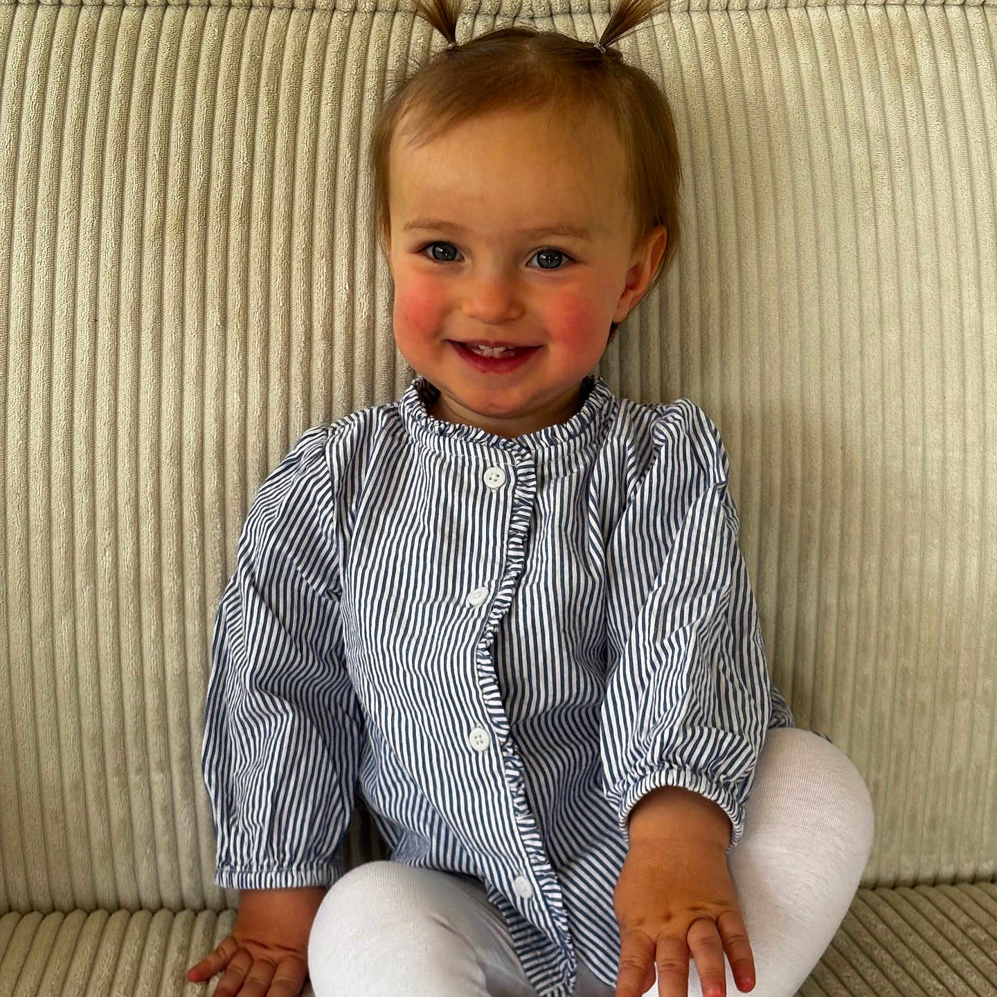 Mila participe au concours pour gagner de l'argent avec cette photo : toddler, child, smiling, pigtails, striped_shirt, white_leggings, sitting, couch, beige, soft_furniture, happy, portrait, indoors, cute, young_child, person, baby, small_hands, feet, comfortable