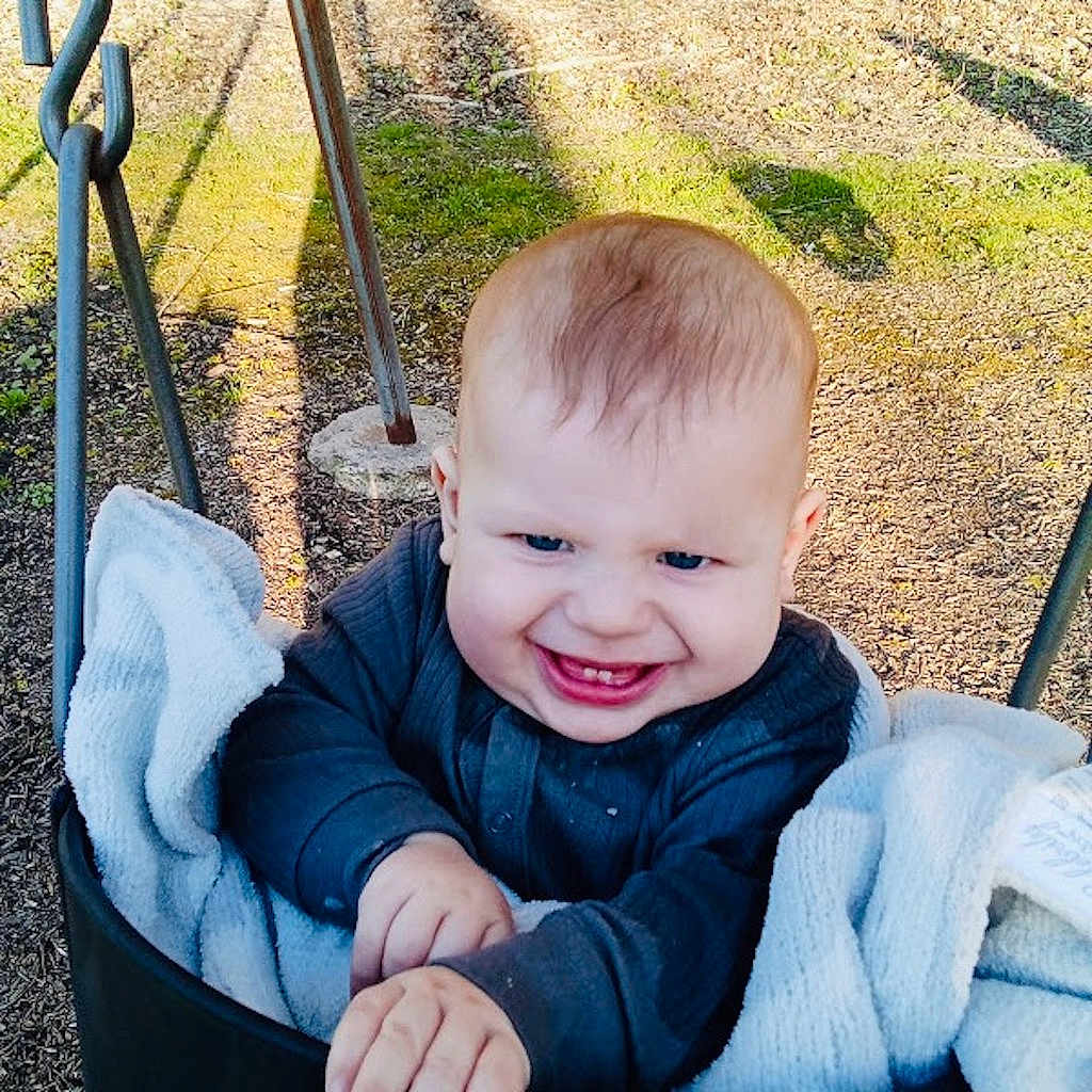 Mayhem joined the competition — help win amazing prizes! baby, clothing, coat, face, grass, happy, head, laughing, nature, outdoorplayarea, outdoors, park, person, photography, plant, playarea, portrait, smile, swing, toy