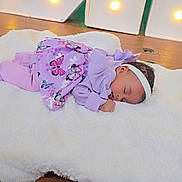 Icyss joined the competition — help win amazing prizes! baby, infant, sleeping, headband, purple_clothing, butterfly_pattern, white_blanket, wooden_surface, decorative_lights, indoor, cozy, newborn, peaceful, portrait, lying_down, soft_texture, sleeping_pose, resting, tiny_hand, newborn_outfit