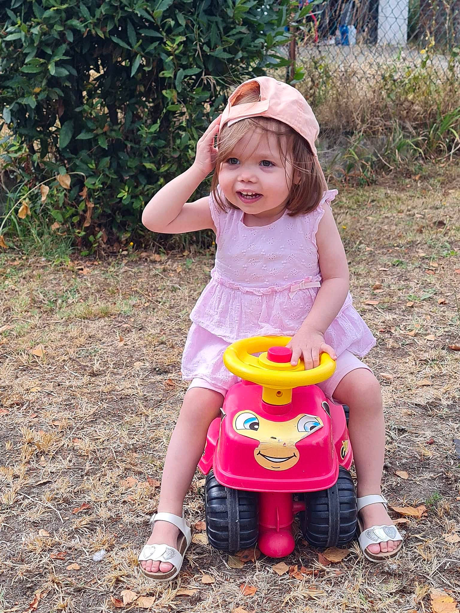 Helena a rejoint le concours — aidez-le/la à gagner de superbes lots ! baby_toddler_clothing, fun, grass, hand, happy, hat, headwear, leisure, magenta, people_in_nature, person, pink, plant, recreation, shoe, sitting, smile, sneakers, toddler, toy