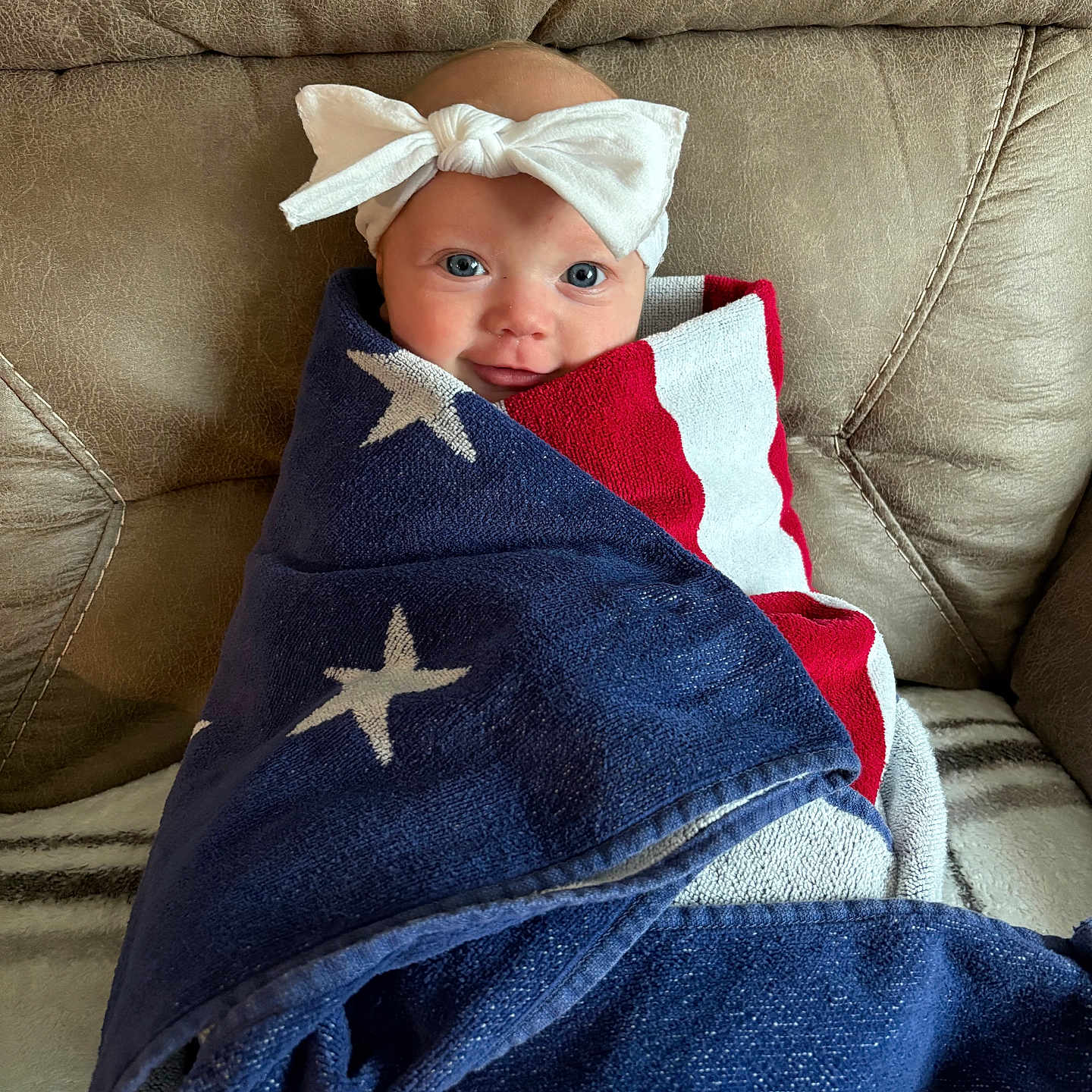 Maibel joined the competition — help win amazing prizes! baby, infant, blanket, headband, bow, couch, fabric, stars, stripes, red, white, blue, face, smile, child, wrapped, seated, comfort, indoor, portrait