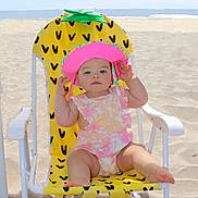 Alexandria is registered to the contest to win money with this photo: baby, beach, cap, chair, clothing, coast, face, furniture, hat, head, nature, outdoors, person, photography, portrait, sea, shoreline, summer, swimwear, water