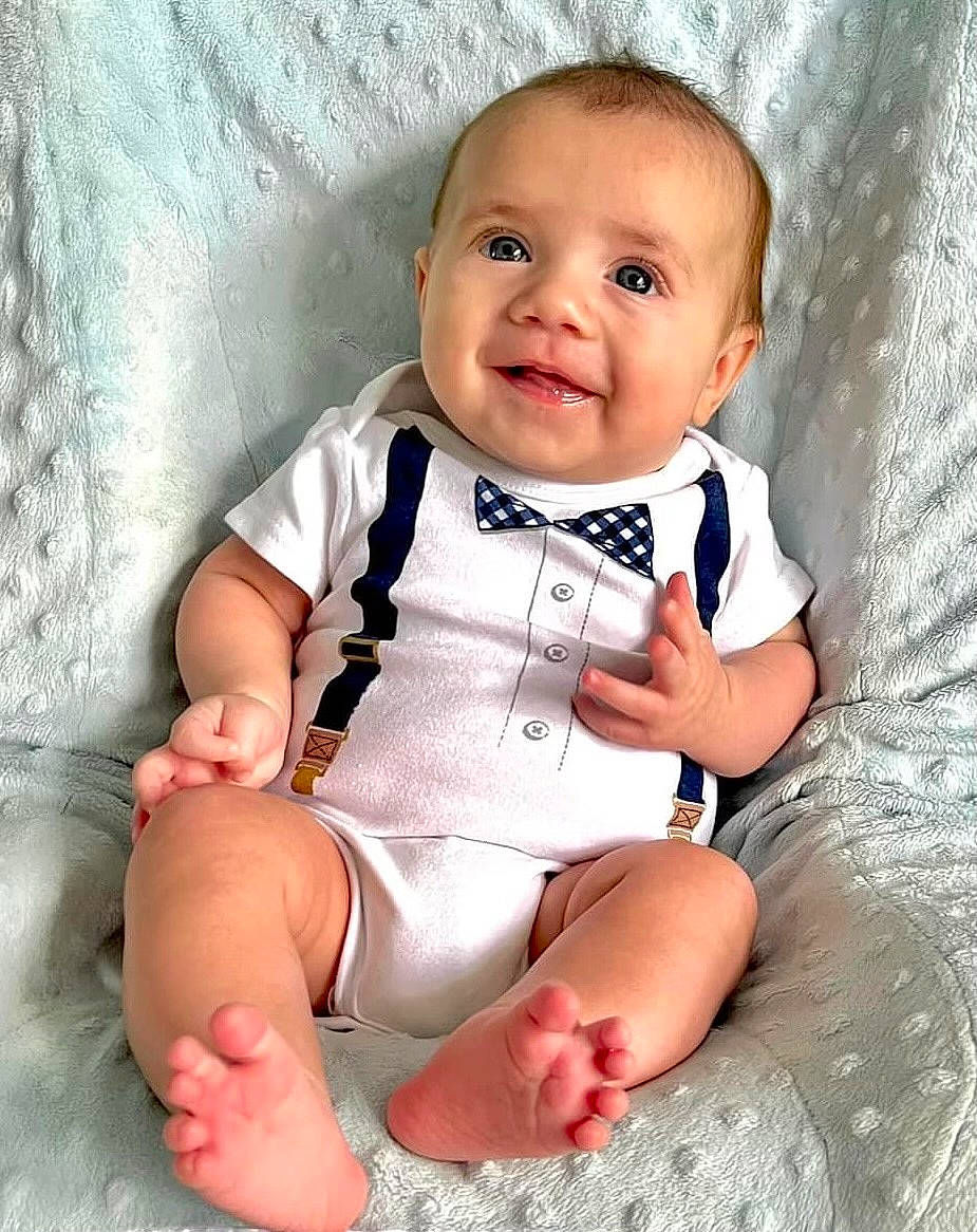 John is registered to the contest to win money with this photo: baby, baby_toddler_clothing, cheek, child, comfort, eye, finger, happy, head, human_leg, iris, joy, pattern, person, sitting, skin, sleeve, smile, stomach, thigh