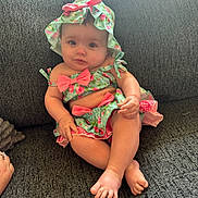 Kayleigh is registered to the contest to win money with this photo: baby, child, infant, couch, clothing, hat, floral_pattern, cute, portrait, smile, skin, feet, hand, sitting, indoor, person, apparel, young, relaxing, cozy