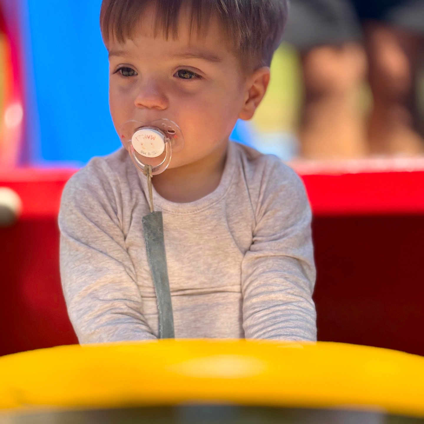 Ayden Vincent participe au concours pour gagner de l'argent avec cette photo : baby, blurry_background, casual_clothing, child, curious, cute, daylight, face, infant, outdoor, pacifier, person, play, playground, short_hair, sitting, toddler, toy, yellow, young_child