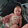 baby, infant, onesie, clothing, blanket, bed, pillow, child, face, foot, hand, skin, person, indoors, cute, expression, casual, comfort, resting, young
