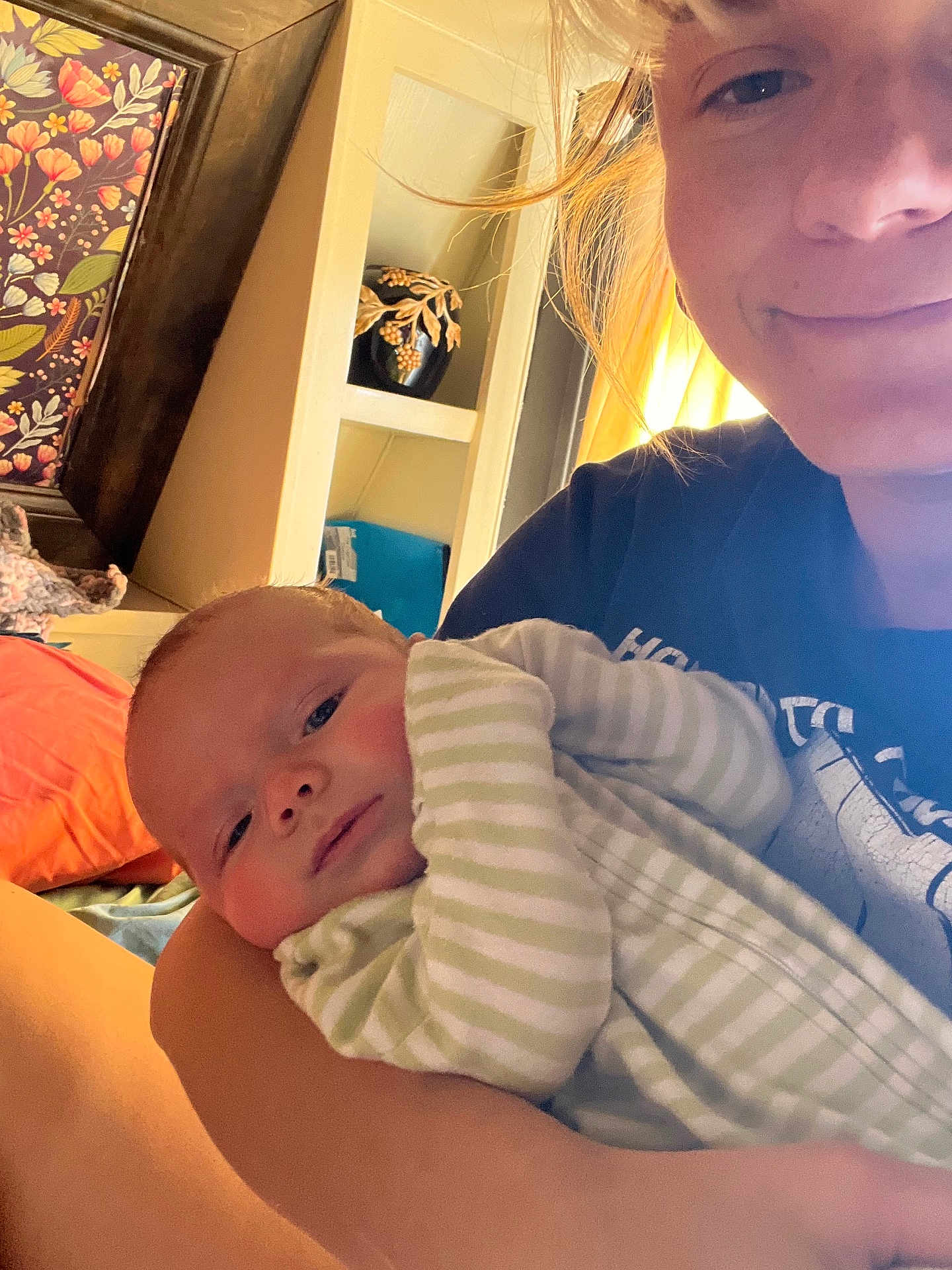 Wyatt is registered to the contest to win money with this photo: baby, adult, smile, indoor, portrait, striped_clothing, onesie, arm, face, window, light, flower_art, decor, candid, holding, warm_light, skin, hair, person, child