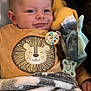baby, infant, smiling, face, blanket, plush_toy, pacifier, clothing, lion_design, onesie, cozy, child, cute, indoors, soft_texture, comfort, happy, young, resting, closeup