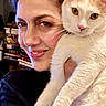 Pepe is registered to the contest to win money with this photo: animal, bookshelf, cat, cozy, cream_cat, cute, domestic, face, friendly, furniture, holding, home, indoor, looking_at_camera, person, pet, portrait, relaxed, smiling, woman