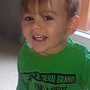 Kelyan participe au concours pour gagner de l'argent avec cette photo : child, toddler, smiling, green_shirt, indoor, natural_light, face, person, hair, happy, jeans, window, expression, portrait, casual_clothing, young_child, cute, standing, light, background