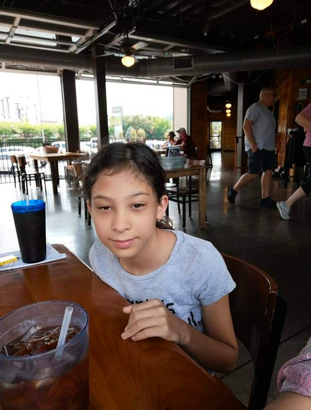 Dani joined the competition — help win amazing prizes! chair, distilled_beverage, drink, event, flooring, fun, joy, leisure, non_alcoholic_beverage, person, recreation, restaurant, room, shorts, sitting, soft_drink, t_shirt, table, tableware, tourism