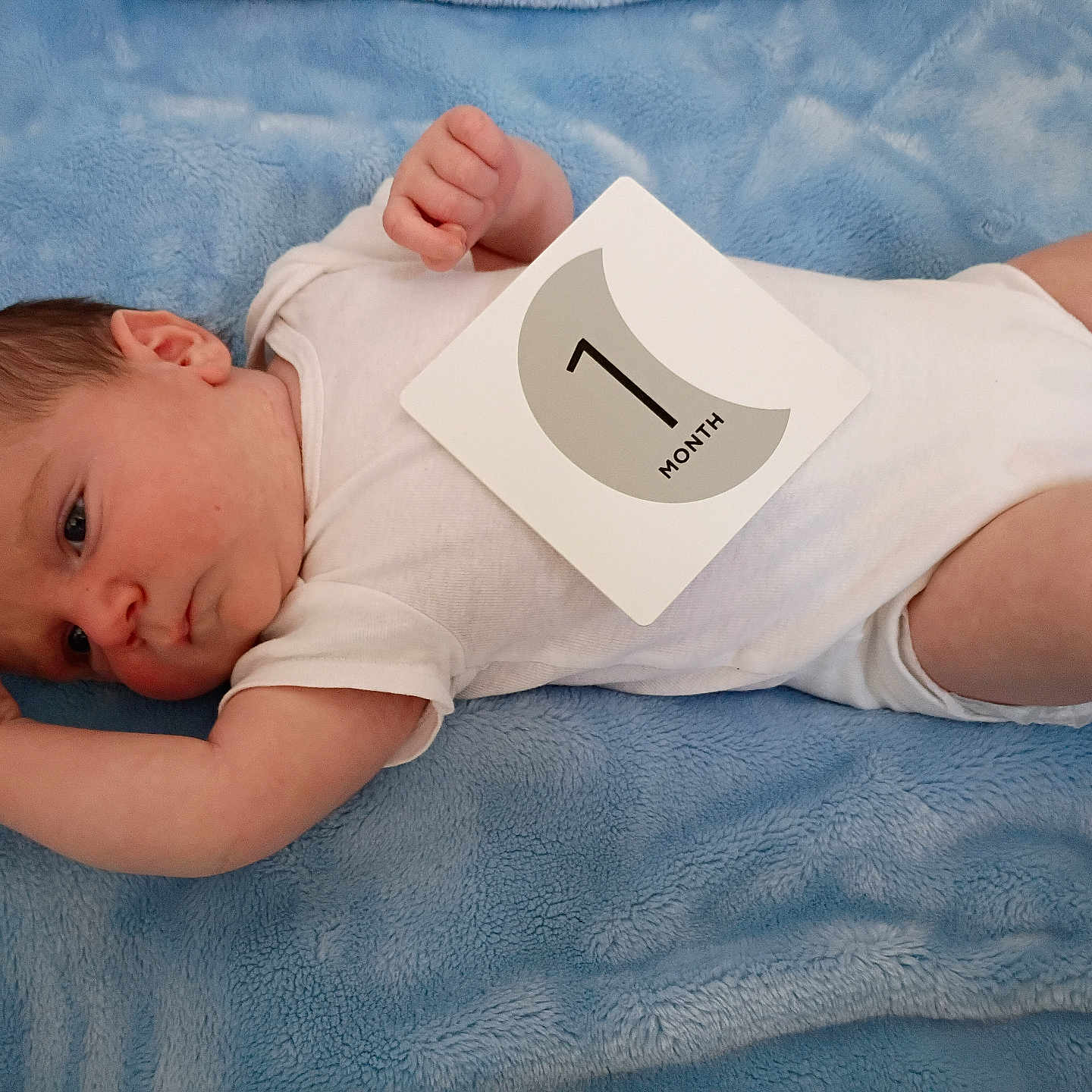 Ian joined the competition — help win amazing prizes! baby, background, blanket, blue, child, cute, expression, face, fingers, head, infant, lying_down, milestone_card, newborn, one_month, onesie, person, skin, small, soft