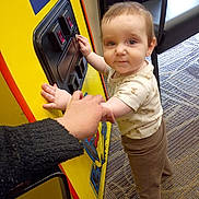 Ian joined the competition — help win amazing prizes! toddler, child, arcade_machine, yellow, free_play_sign, carpet, barefoot, clothing, hand, adult, chair, indoor, person, floor, toy, game, support, window_light, curious, standing