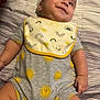 baby, infant, smiling, onesie, hat, bed, bedding, striped, pattern, sun, yellow, grey, cute, child, lying_down, happy, face, skin, hand, chubby