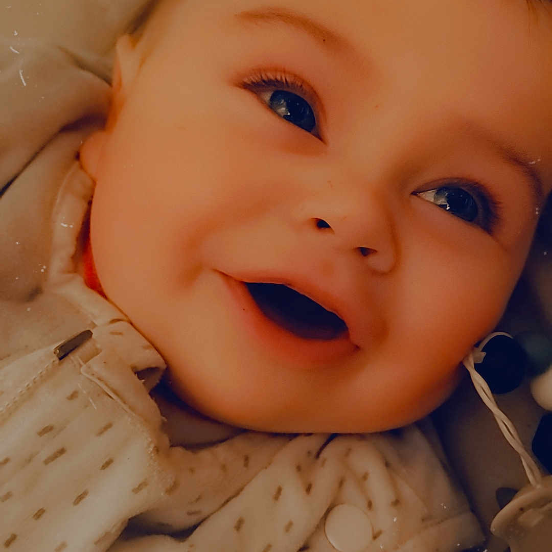 Eden participe au concours pour gagner de l'argent avec cette photo : baby, babylaughing, bodypart, clothing, couch, face, finger, furniture, hand, happy, head, knitwear, laughing, mouth, newborn, person, photography, portrait, smile, sweater