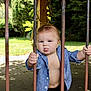 baby, child, tongue, iron_bars, blue_shirt, shirt, outdoor, garden, grass, tree, stone_wall, fence, hand, face, expression, person, nature, daylight, cute, playful