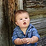 baby, child, denim_shirt, curious, wooden_wall, outdoor, portrait, cute, chubby_cheeks, hands, expression, rustic, natural_light, infant, person, young_child, casual_clothing, texture, background, photography