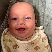 Archie-Lee-pattison is registered to the contest to win money with this photo: baby, smiling, face, bib, paw_prints, stars, blanket, infant, cute, happy, clothing, texture, closeup, portrait, child, soft, cozy, lying_down, skin, expression