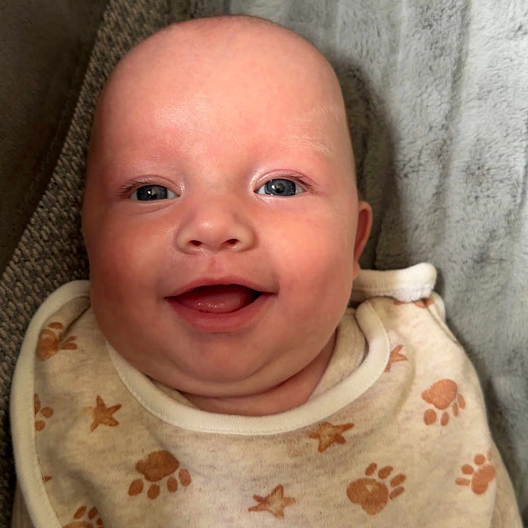 Archie-Lee-pattison is registered to the contest to win money with this photo: baby, bib, blanket, child, closeup, clothing, cozy, cute, expression, face, happy, infant, lying_down, paw_prints, portrait, skin, smiling, soft, stars, texture