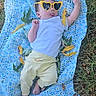 Vivian is registered to the contest to win money with this photo: baby, infant, child, portrait, outdoor, grass, blanket, crocheted_blanket, sunglasses, heart_shaped_sunglasses, tongue_out, lying_down, white_shirt, yellow_pants, barefoot, photography, playful, garden, leaves, natural_light