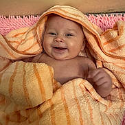 Valerie joined the competition — help win amazing prizes! baby, smiling, towel, orange_stripes, pink_rug, cute, infant, face, happy, wrapped, soft_texture, indoors, child, skin, head, hand, expression, blanket, comfort, portrait