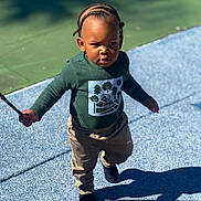 Rocket joined the competition — help win amazing prizes! toddler, child, outdoor, walking, sunlight, shadow, cornrows, stick, green_shirt, beige_pants, footwear, playground, texture, confident, determined, person, young_child, daylight, casual_clothing, nature