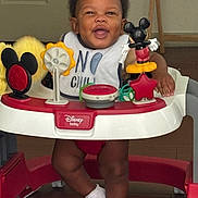 Rocket joined the competition — help win amazing prizes! baby, bib, child, clothing, disney, door, face, feet, floor, furniture, happy, indoor, mickey_mouse, person, playtime, smiling, socks, toy, walker, wooden_floor