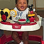 baby, bib, child, clothing, disney, door, face, feet, floor, furniture, happy, indoor, mickey_mouse, person, playtime, smiling, socks, toy, walker, wooden_floor