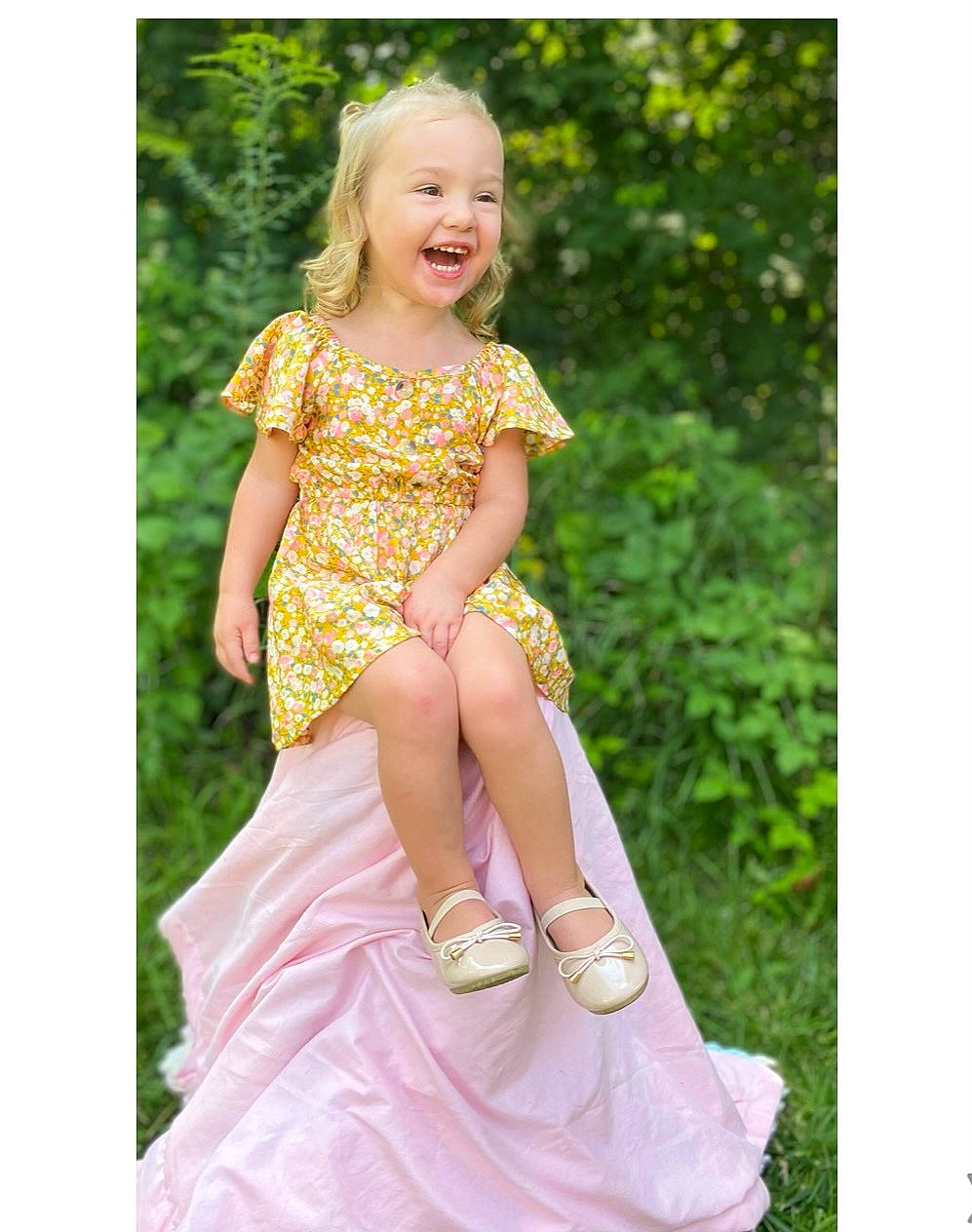 Makenna is registered to the contest to win money with this photo: bridal_party_dress, day_dress, dress, face, fashion_design, footwear, formal_wear, gown, grass, happy, human_body, magenta, one_piece_garment, pattern, people_in_nature, person, pink, sleeve, smile, toddler