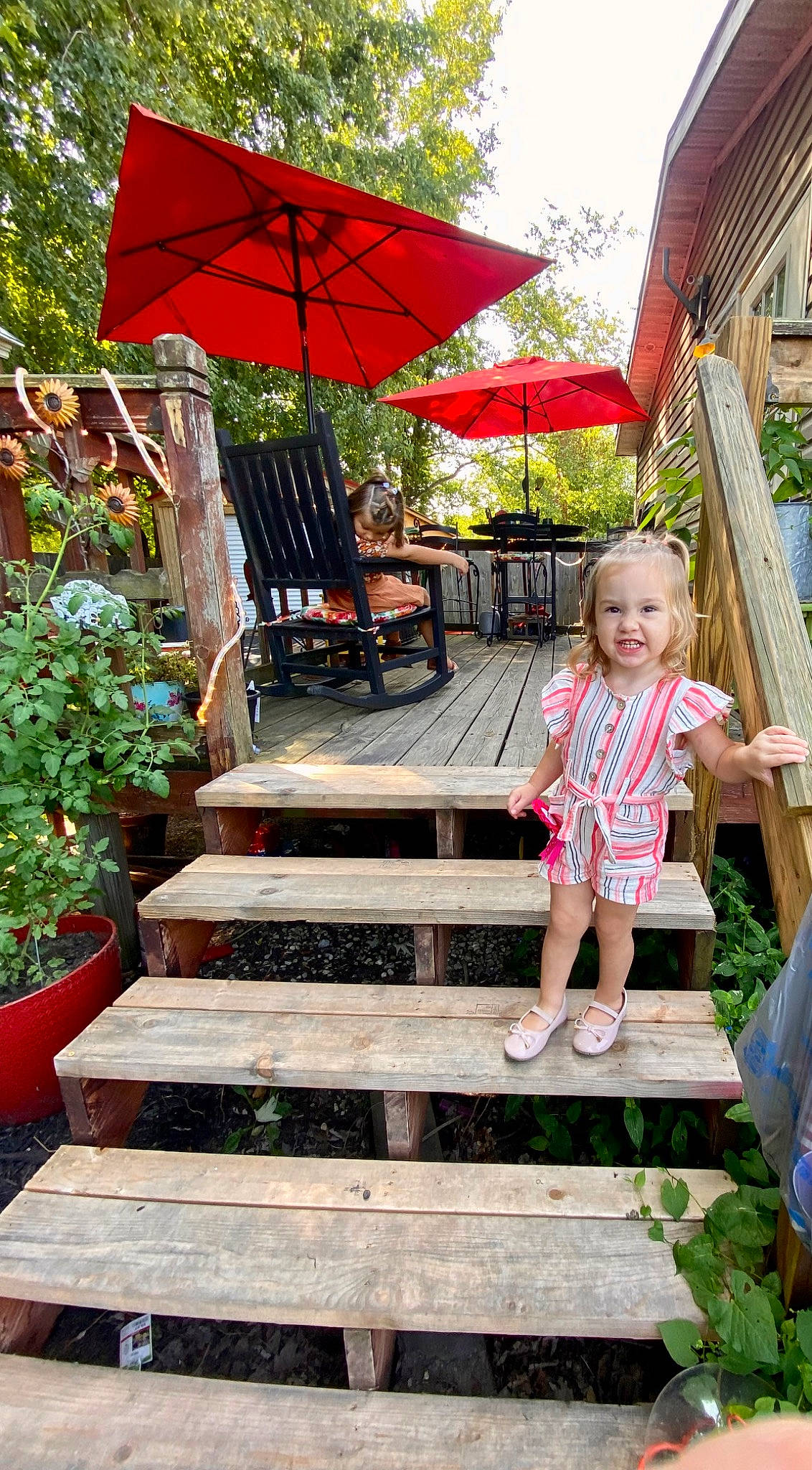 Makenna is registered to the contest to win money with this photo: botany, flowerpot, garden, grass, green, house, landscape, leaf, leisure, outdoor_furniture, person, plant, public_space, recreation, red, shade, shorts, summer, toddler, tree