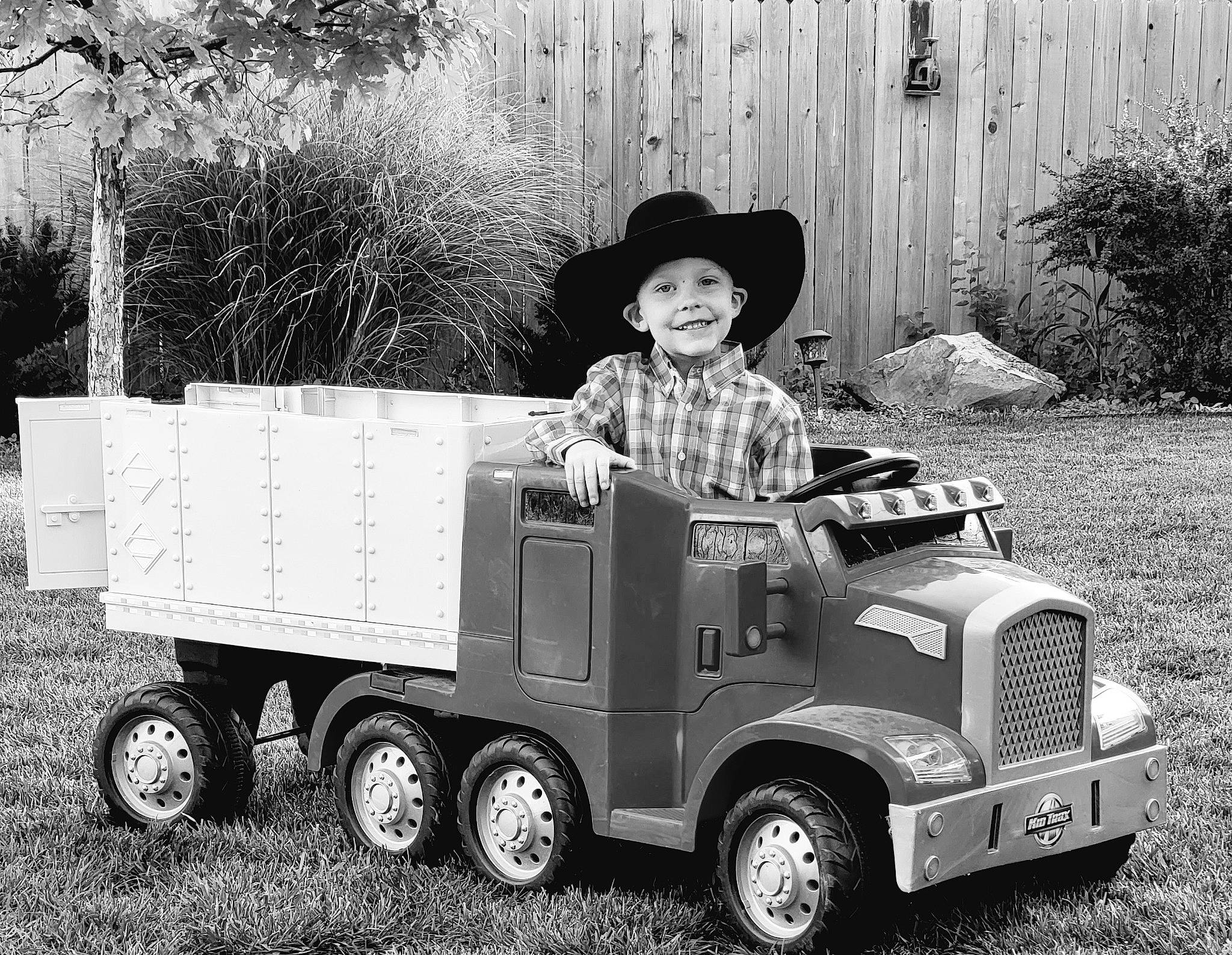 Charly joined the competition — help win amazing prizes! automotive_exterior, automotive_tire, automotive_wheel_system, black, classic, fender, grass, grille, hat, headwear, joy, mode_of_transport, motor_vehicle, person, plant, smile, tire, toddler, tread, truck