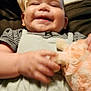 baby, smiling, plush_toy, bed, blanket, pillow, child, infant, happy, cute, clothing, striped_shirt, soft_toy, indoor, relaxing, person, portrait, hand, face, cozy
