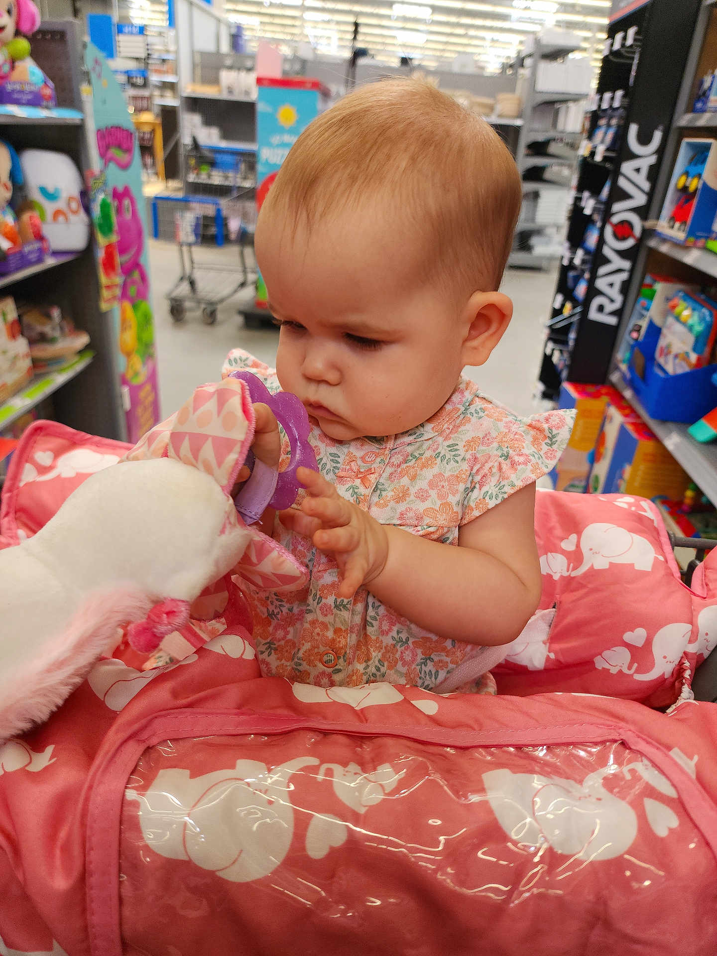 Lily joined the competition — help win amazing prizes! baby, child, shopping_cart, toy, plush, unicorn, teething_ring, store, shelf, shopping, pink, floral_dress, infant, girl, cute, indoor, retail, curious, person, cart