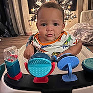 Rafael joined the competition — help win amazing prizes! baby, infant, walker, toy, face, child, indoor, christmas_tree, holiday, curious, smiling, clothing, floor, furniture, fan, blanket, home, decor, lighting, portrait