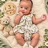 baby, infant, child, three_months, portrait, lying_down, smiling, floral_dress, dress, teddy_bear, blanket, flowers, daisies, greenery, wooden_sign, milestone_photo, nursery, cozy, socks, indoor