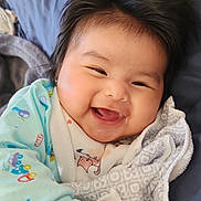 Aitana Aliz is registered to the contest to win money with this photo: baby, smiling, happy, blanket, onesie, infant, cute, child, face, hair, lying_down, cozy, patterned_blanket, soft_texture, indoors, portrait, cheerful, young_child, skin, hand