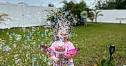 Stormy joined the competition — help win amazing prizes! child, bubble_blower, bubbles, pink_shirt, outdoor, grass, fence, toy, play, garden, daytime, greenery, happy, person, nature, summer, fun, backyard, tree, plant
