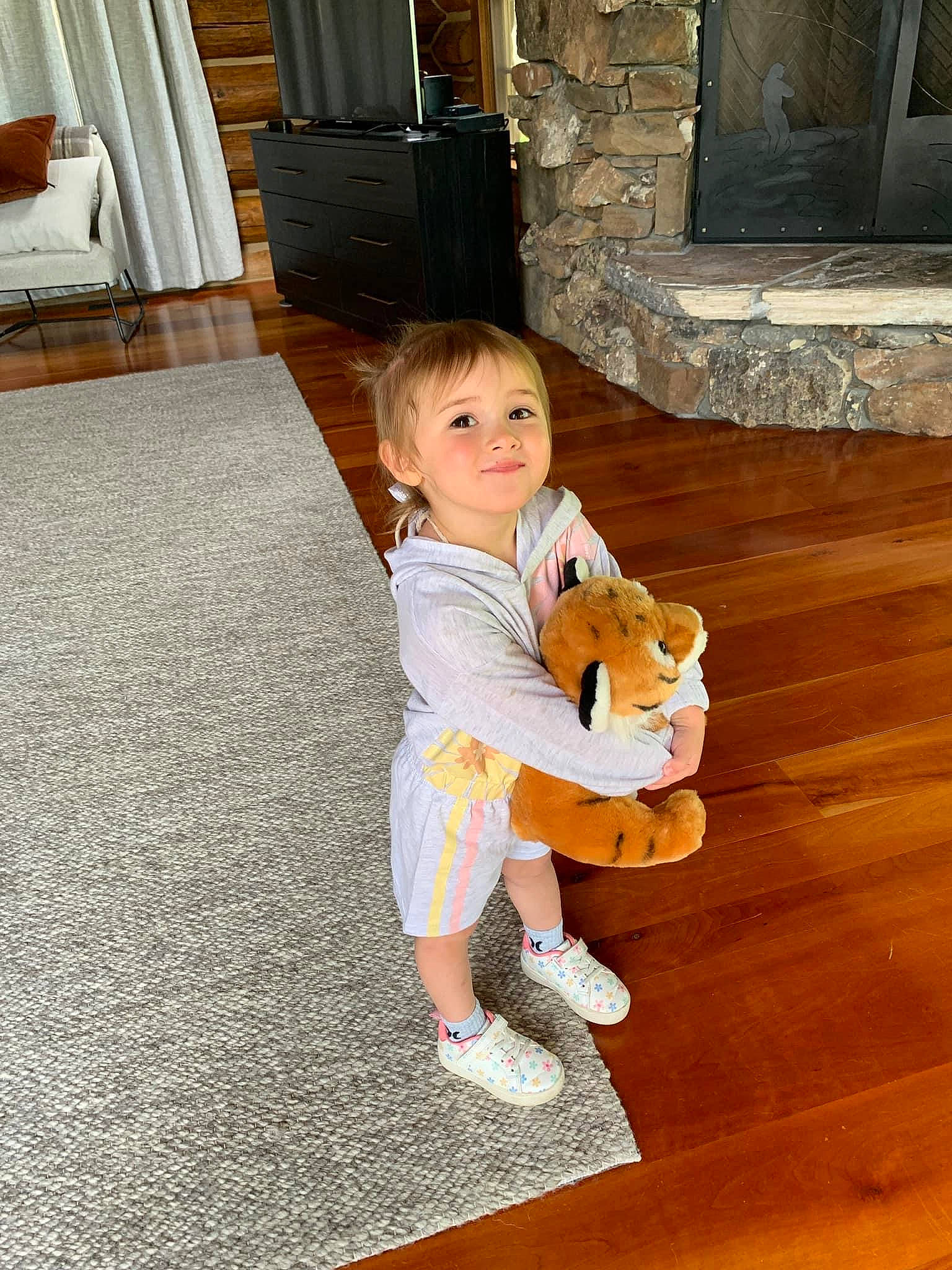 Haisley joined the competition — help win amazing prizes! baby_toddler_clothing, cabinetry, child, companion_dog, door, floor, flooring, fun, hardwood, human_body, human_leg, joy, person, room, sitting, smile, thigh, toddler, toy, wood