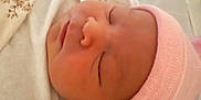 Dolly joined the competition — help win amazing prizes! baby, bed, blanket, child, closeup, cozy, cute, face, head, indoor, infant, newborn, peaceful, pink_hat, portrait, resting, sleeping, soft, swaddled, warm
